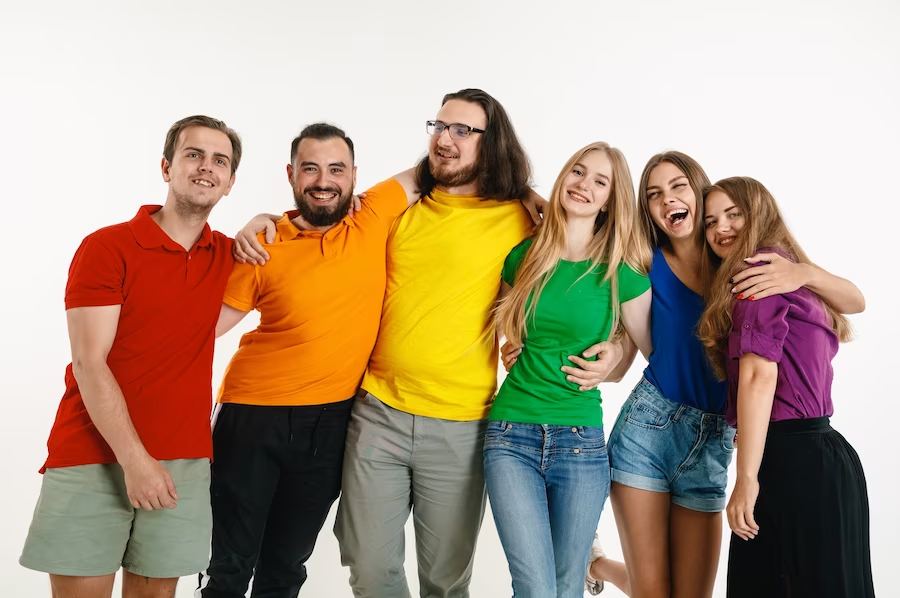 Diverse group of people with various genders, wearing shirts in a rainbow of colors