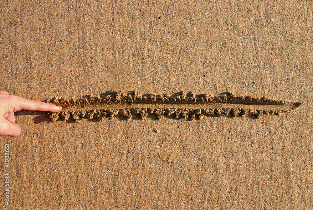 hand drawing a straight line in the sand