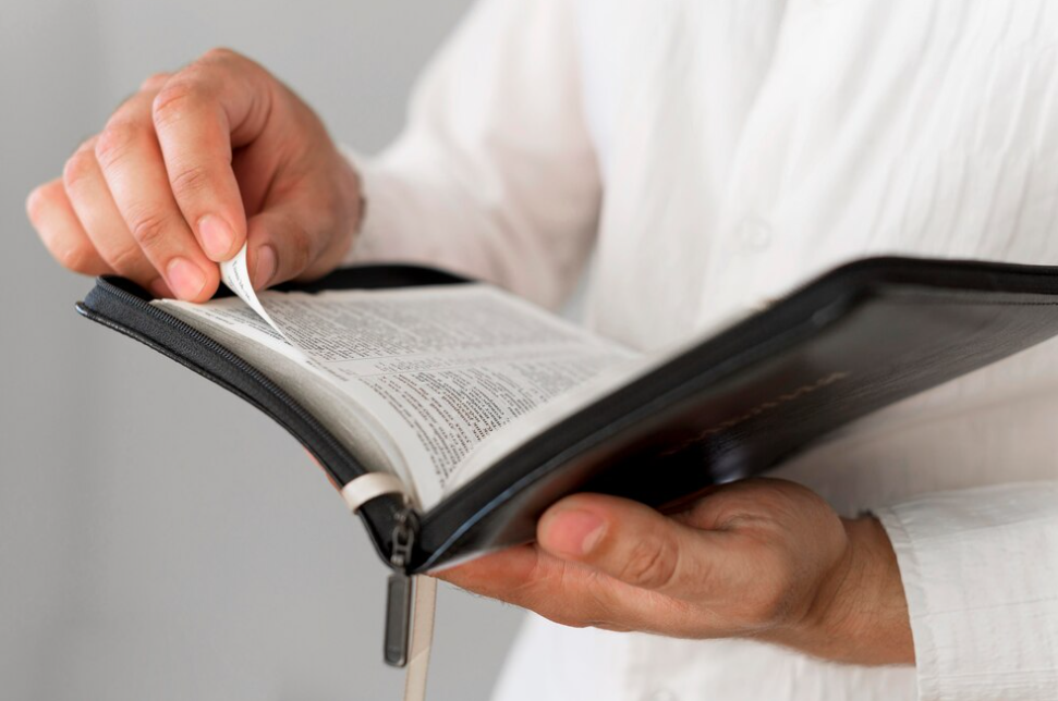 The person in white shirt holds an open book and turns the page